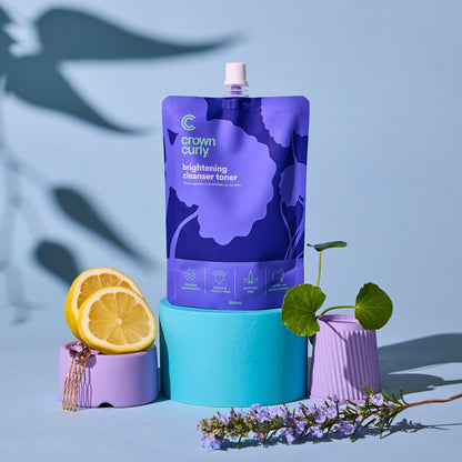 Purple skincare product packaging with lemons and a plant on a blue background