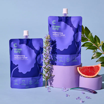 Crown Curly skincare products on a blue background with lavender and grapefruit.