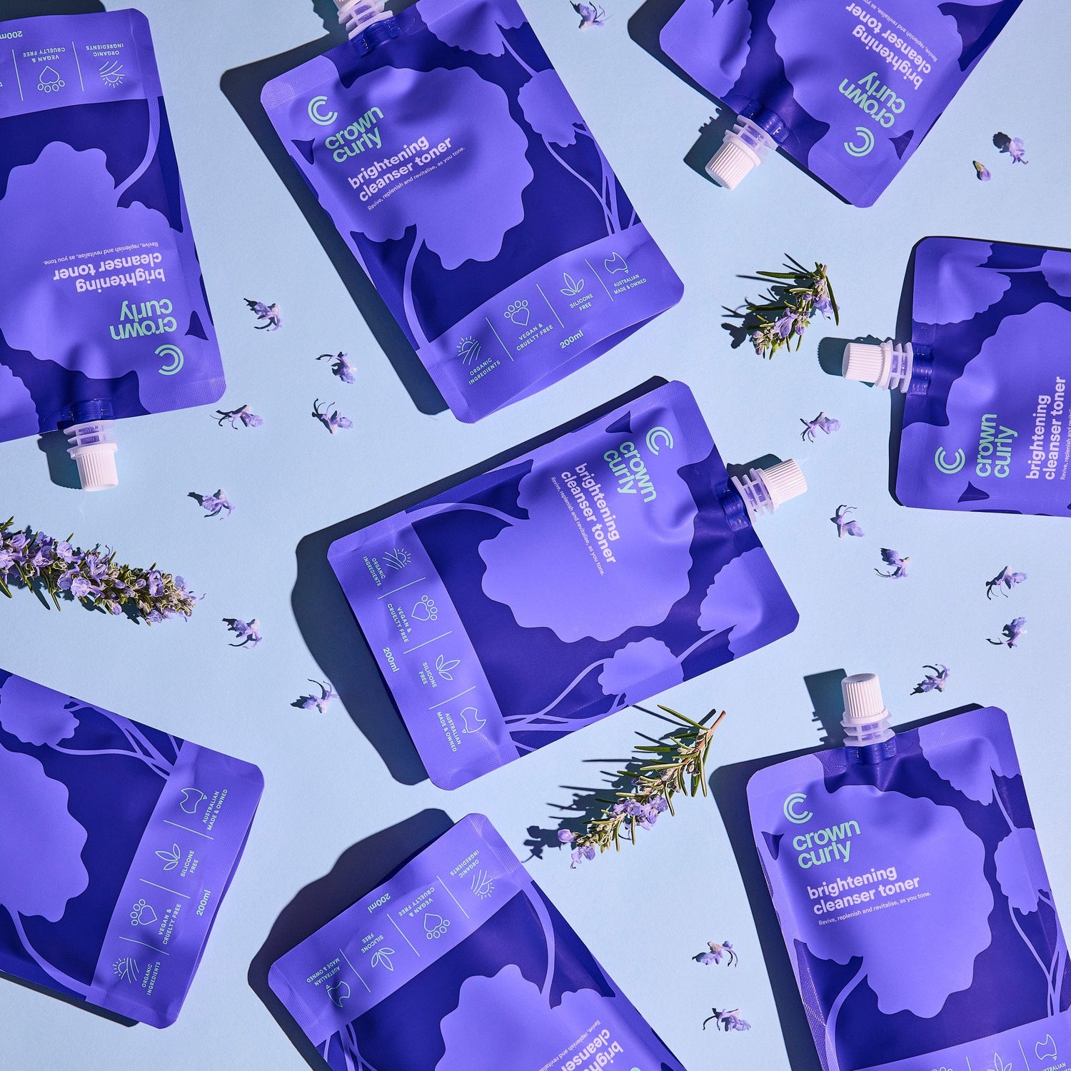 Pattern of purple haircare product packaging on a blue background with floral elements.